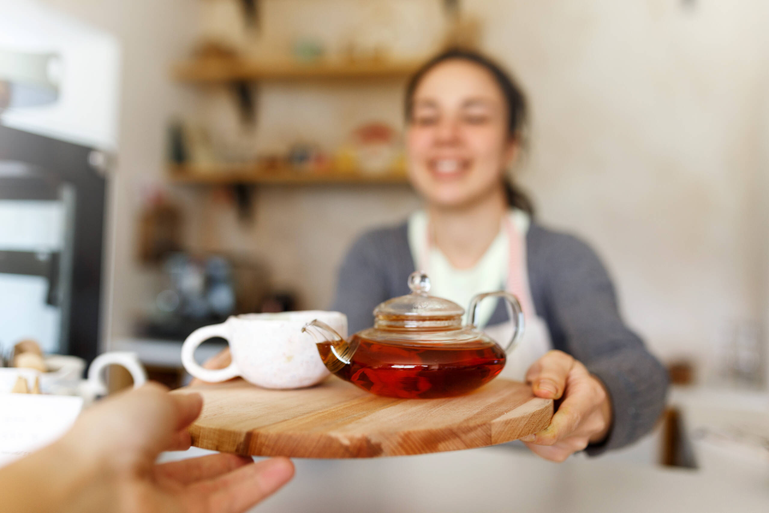 Happy young woman in apron, startup come true. Small business concept. Family business, cafe place. Giving orders, holding tea tray and cup, close up.